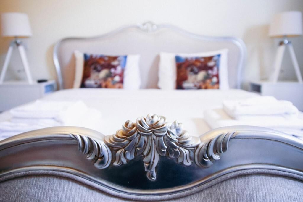 A bed with a decorative headboard, two pillows with floral patterns, and two bedside lamps.