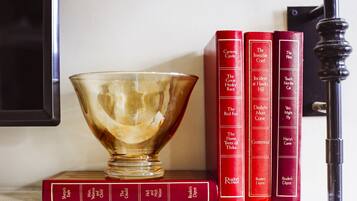 Una colección de libros rojos en una estantería, con un cuenco de vidrio transparente al frente.