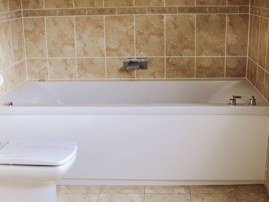 A bathroom with a bathtub, toilet, and a towel rack.