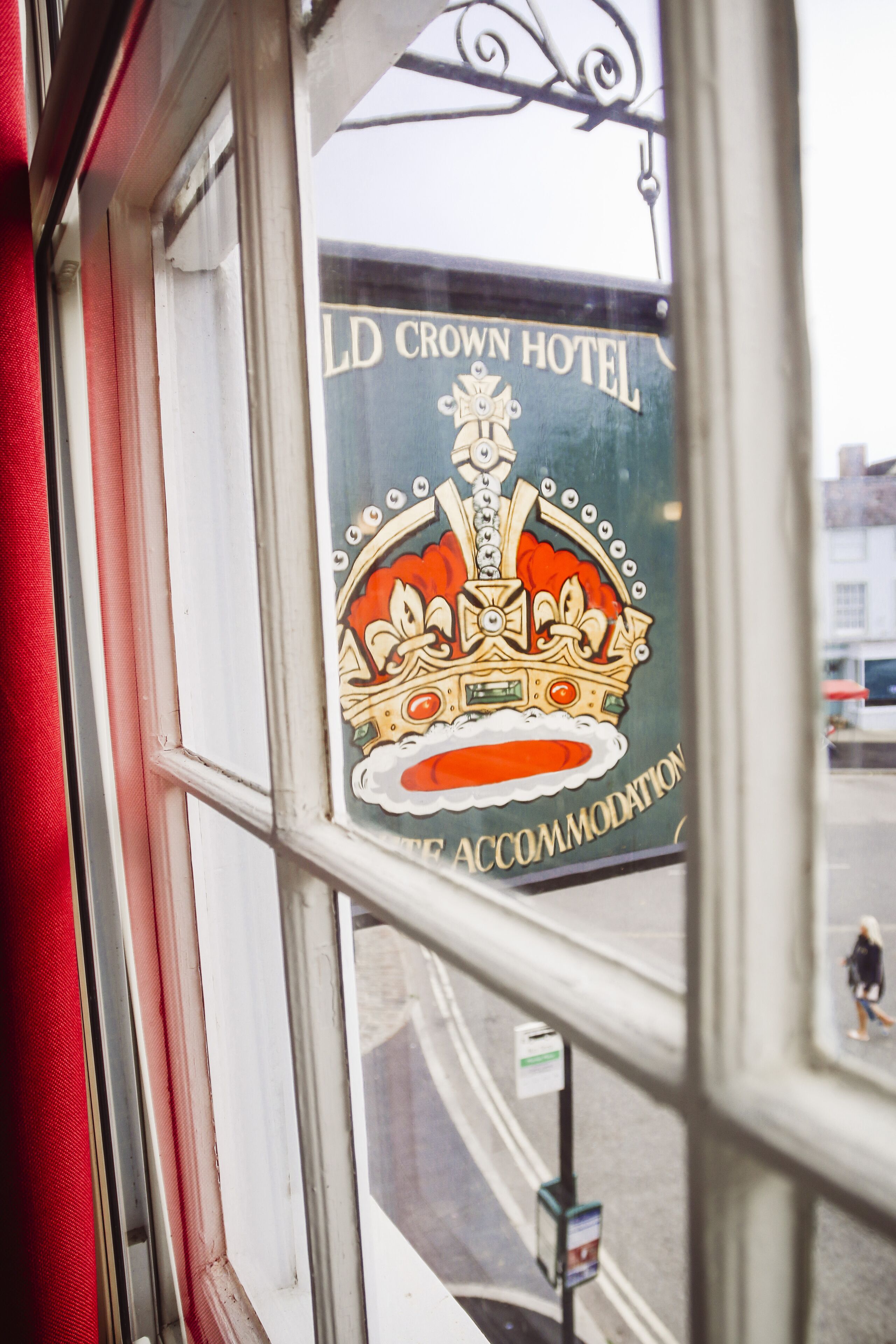 A window with a sign for the Old Crown Hotel, featuring a crown emblem and the text "ACCOMMODATION".