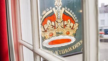 A window with a sign for the Old Crown Hotel, featuring a crown emblem and the text "ACCOMMODATION".
