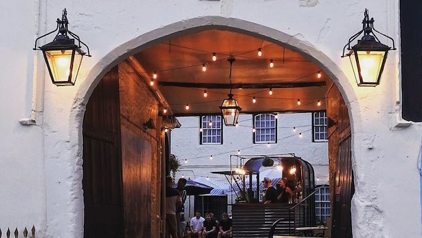 An arched entrance with hanging lights, a staircase, and outdoor seating area. - The Old Crown Coaching Inn (Faringdon)