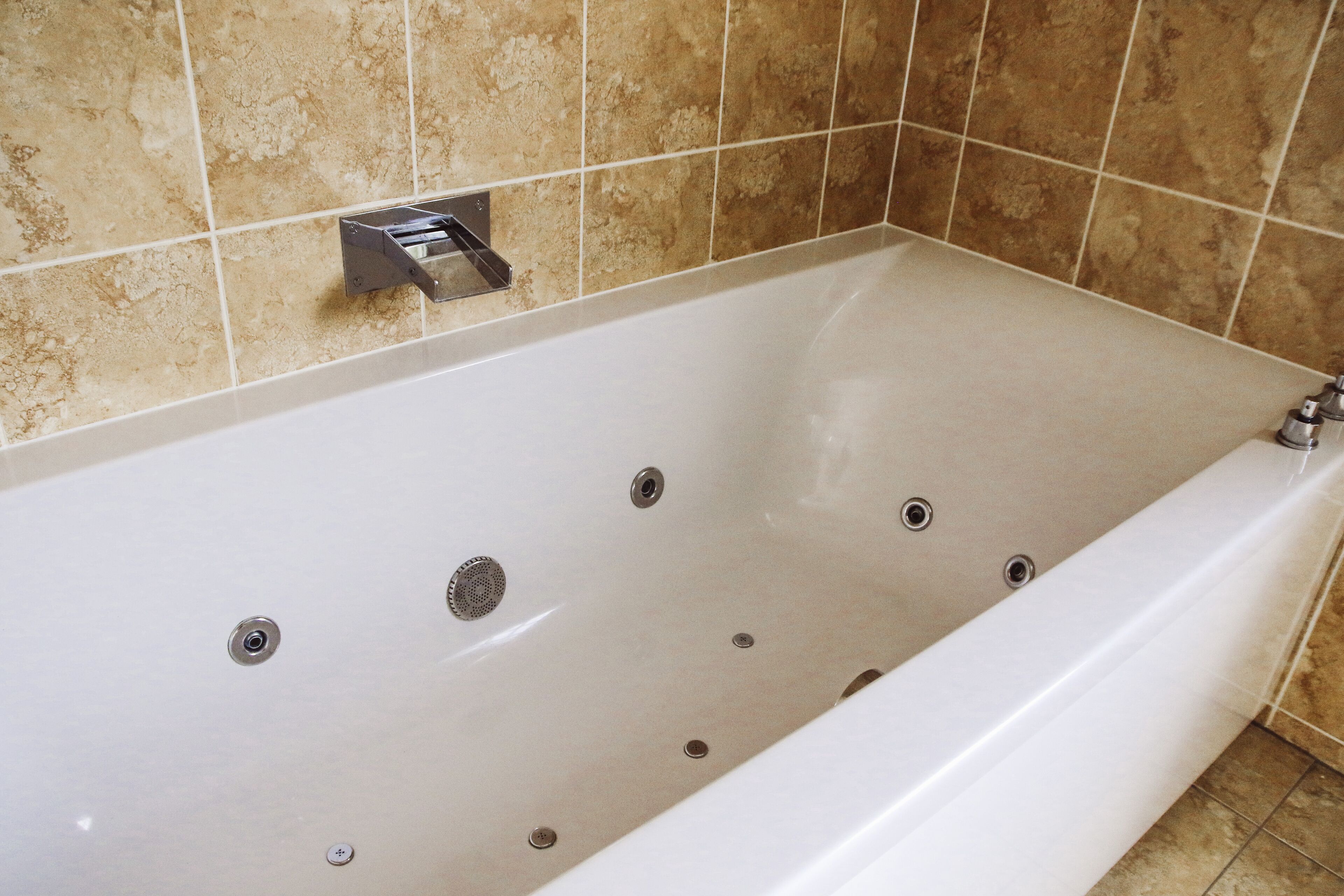 A modern bathroom with a large bathtub, tiled walls, and a showerhead.