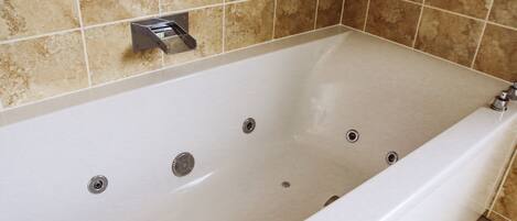 A modern bathroom with a large bathtub, tiled walls, and a showerhead.