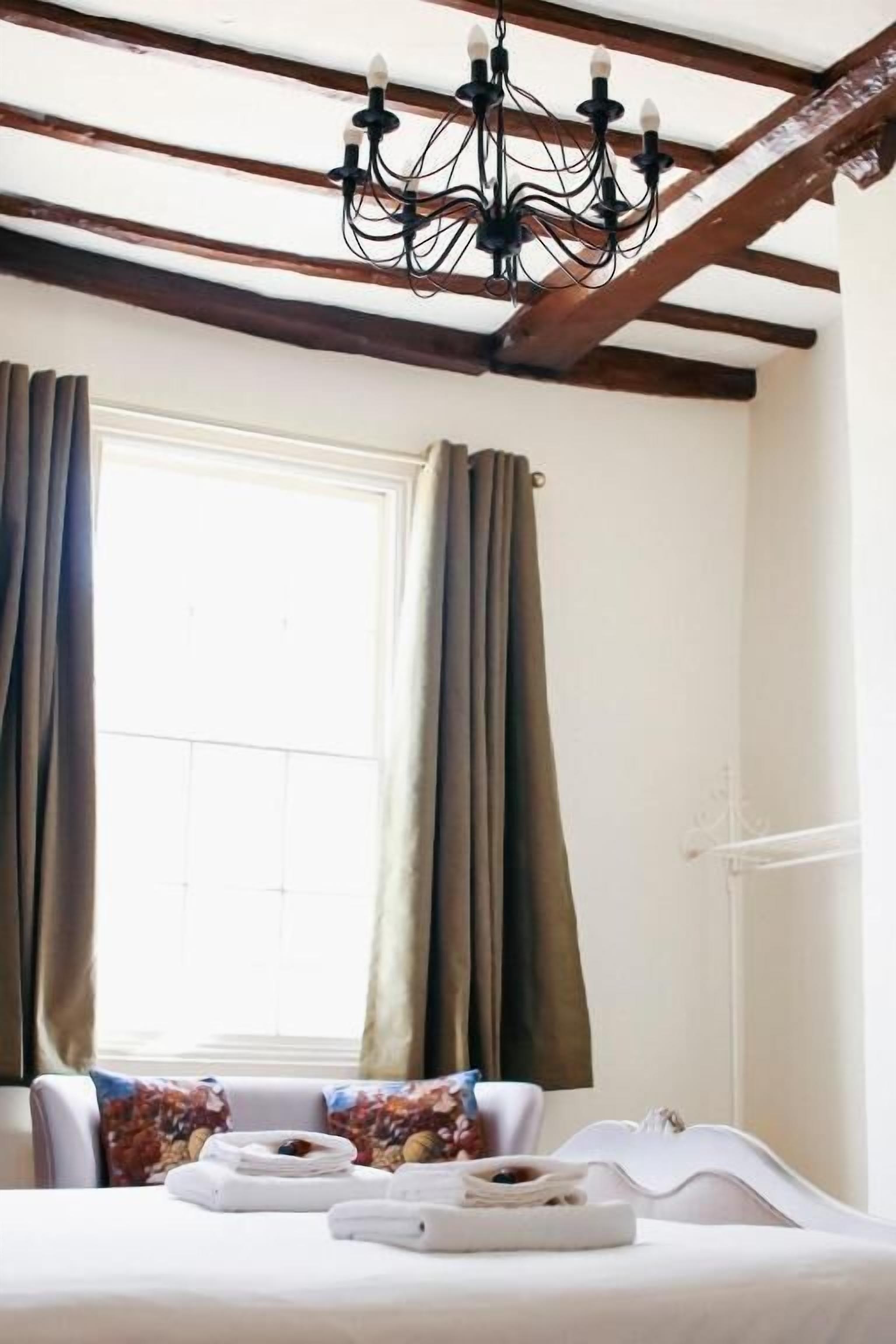 Een kamer met een bed, een kroonluchter en gordijnen.