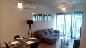 Een moderne woonkamer met een eethoek, een bank en een televisie.