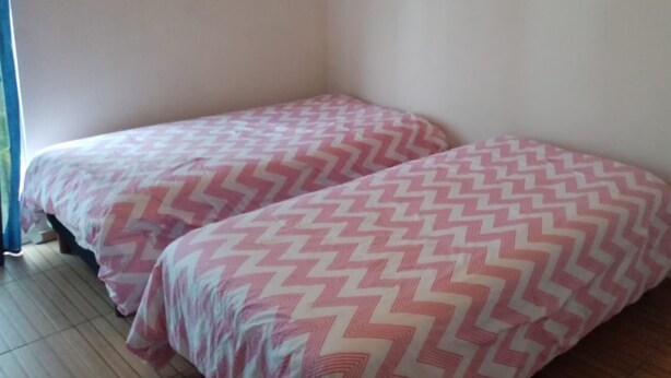 A room with two single beds, each with a pink and white zigzag patterned bedspread. There are two framed pictures on the wall, one with the word "sweet" and the other with "dream." - Modern & Spacious Manzanillo Apartment near all shops (Manzanillo)