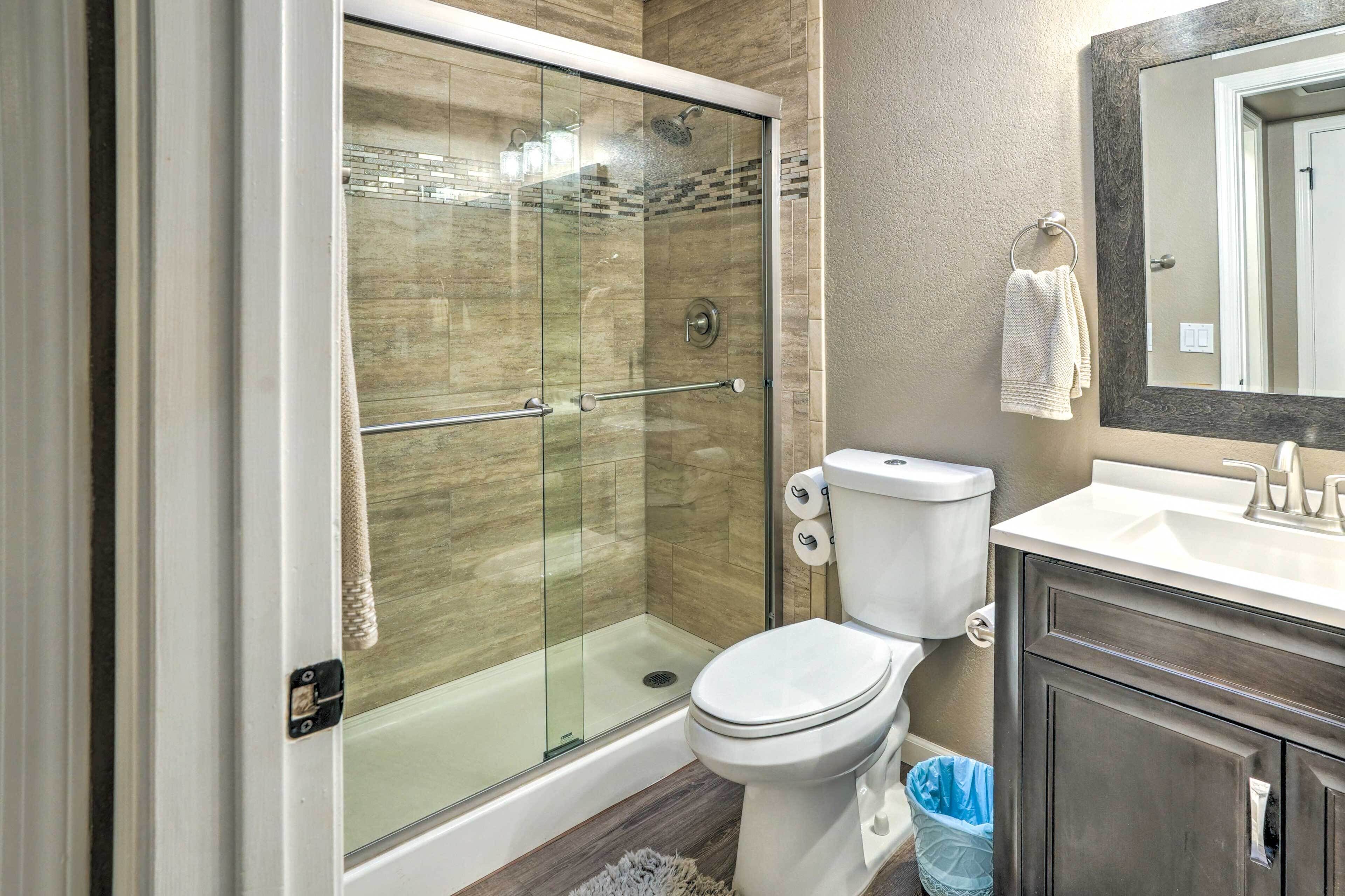 Un baño con ducha de vidrio, inodoro, lavamanos y espejo.