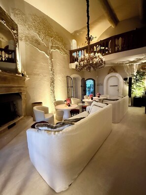 Un salon spacieux avec un grand canapé blanc, une cheminée et un lustre.