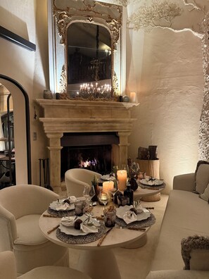 A room with a fireplace, a large mirror, and a table set for dining.