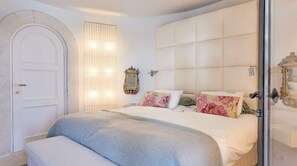 Un dormitorio con una cama grande, un armario, un espejo y una puerta.