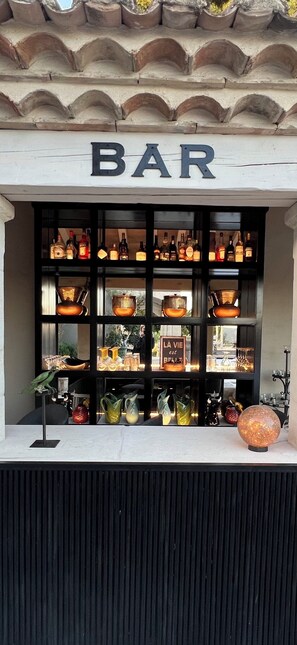 Un bar avec une enseigne au-dessus de l’entrée, des étagères remplies de bouteilles et des objets décoratifs.