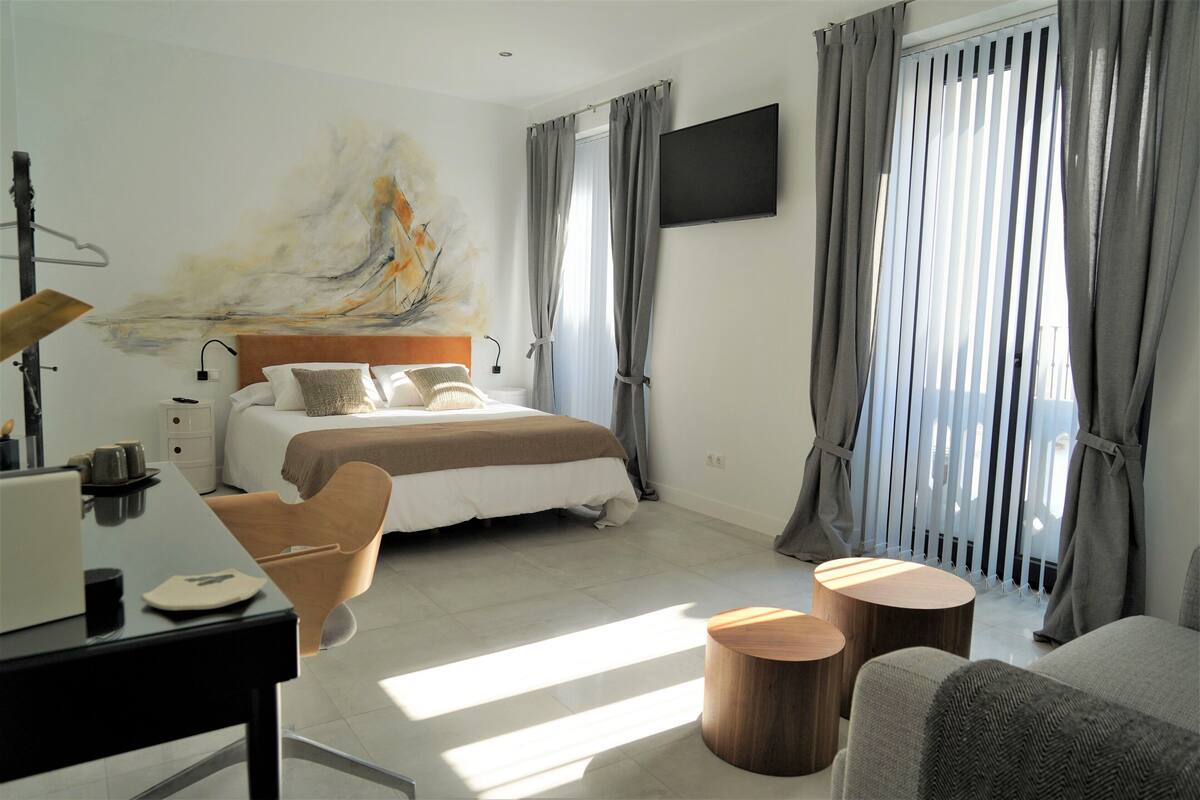A modern hotel room with a bed, a desk, a chair, and a TV.