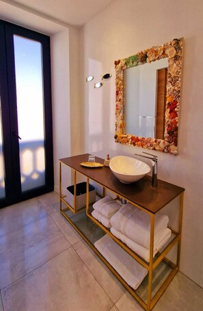 A bathroom with a wooden vanity, a large mirror with a floral frame, a white sink, and a towel rack. - OPUNTIA Boutique hotel (Mijas)