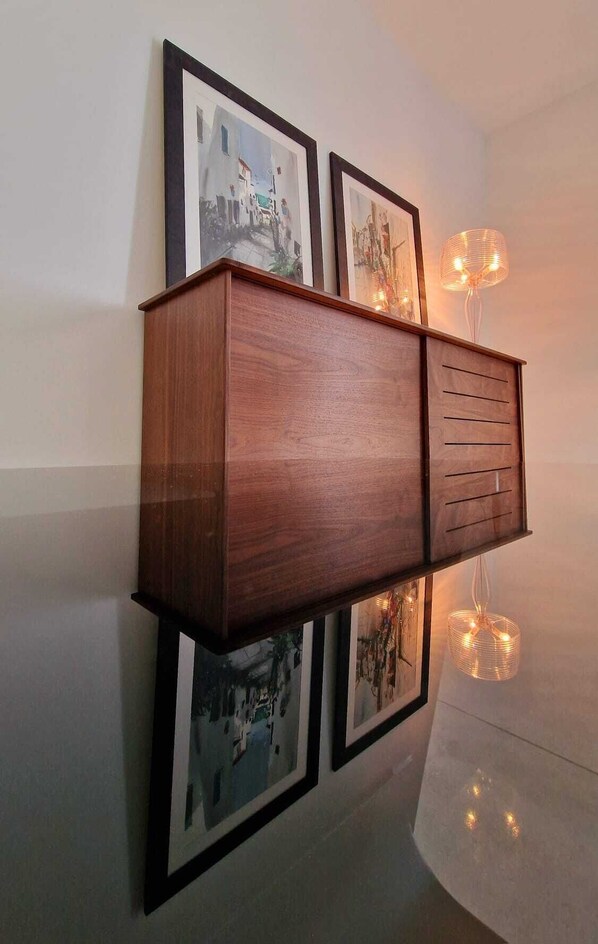 Un mueble de madera con varios cajones, fijado a la pared sobre fotografías enmarcadas.