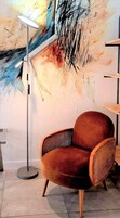 Una habitación moderna con un sillón tapizado marrón, una lámpara de pie y un cuadro abstracto grande en la pared.