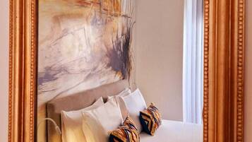 A bedroom with a large mirror, a bed with white linens, and a colorful abstract painting on the wall.