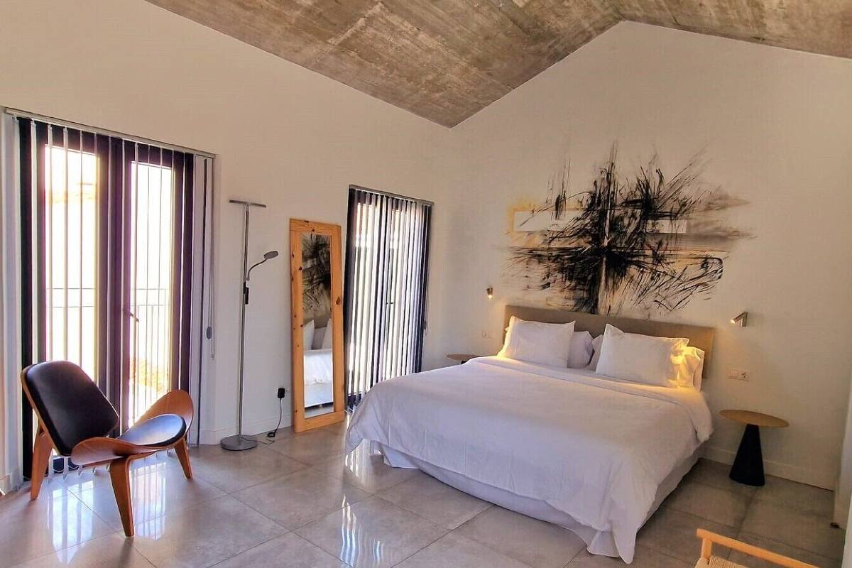 A modern bedroom with a large bed, a chair, and a floor lamp.