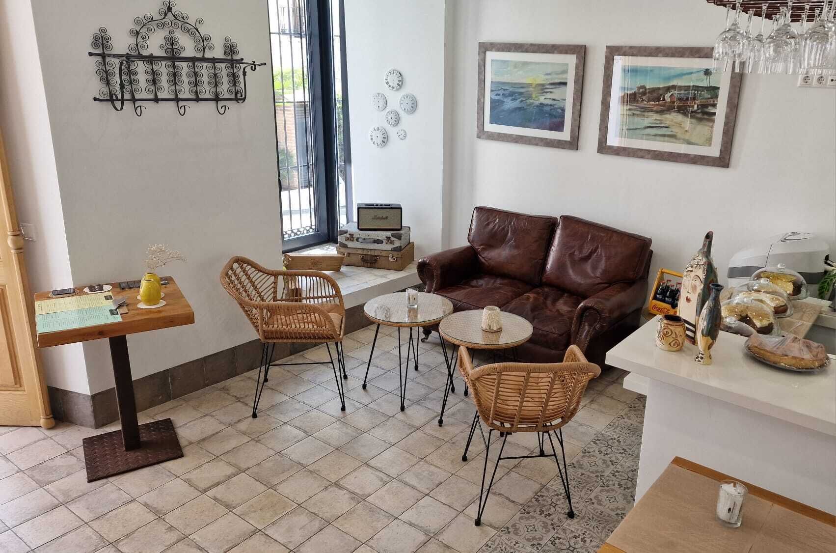 Un salon chaleureux avec un canapé en cuir marron, des fauteuils en osier et une petite table ronde.