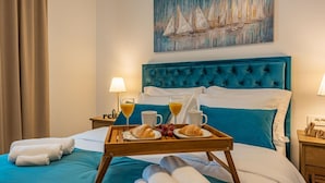 A hotel room with a bed, a tray with croissants and juice, and a painting of sailboats on the wall. - Villa Roza Zadarvillas (Policnik)