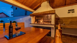 A wooden dining table with a bottle of wine and two glasses, a fireplace, and a view of the outside. - Villa Roza Zadarvillas (Policnik)