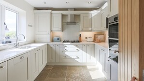 Une cuisine moderne avec des meubles blancs, une cuisinière à gaz et un four encastré.