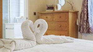Un lit avec deux serviettes disposées en forme de cœur.