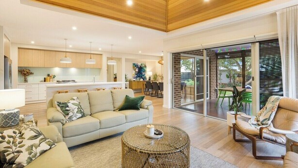 A spacious living area with a sofa, armchair, and coffee table, a kitchen in the background, and a sliding glass door leading to an outdoor patio. - Luxurious Privacy in Exquisite Home, Walk to Golf (Cowes)