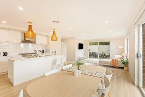 A modern kitchen with white cabinetry, a central island, and pendant lighting.
