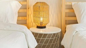 A room with two beds, a round table with a geometric-patterned side table, and a wall-mounted lamp.