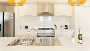 A modern kitchen with stainless steel appliances, a double sink, and pendant lighting.