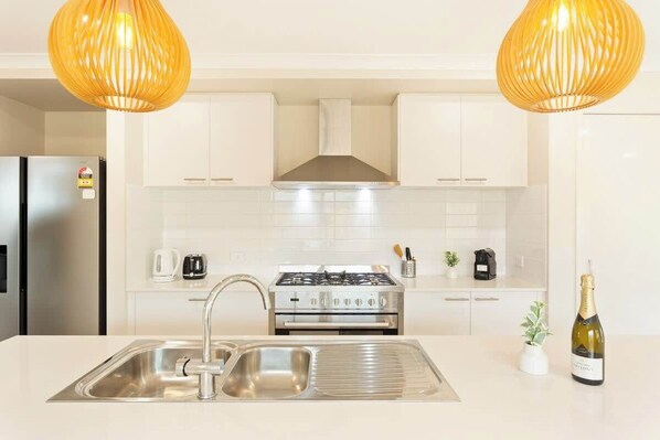 Una cocina moderna con electrodom ésticos de acero inoxidable, un lavamanos doble e iluminación colgante.
