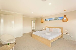 A bedroom with a large bed, a chair, a small table, and two pendant lights.