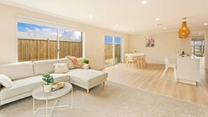 A modern living room with a sofa, coffee table, and dining area.