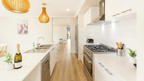 A modern kitchen with white cabinetry, stainless steel appliances, and pendant lighting.