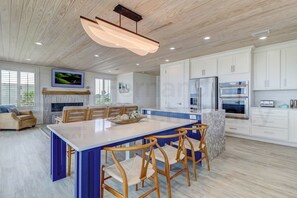Una cocina moderna con una isla grande, armarios blancos y electrodomésticos de acero inoxidable.