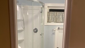 Een badkamer met een douche in een glazen cabine, een toilet en een wastafel.
