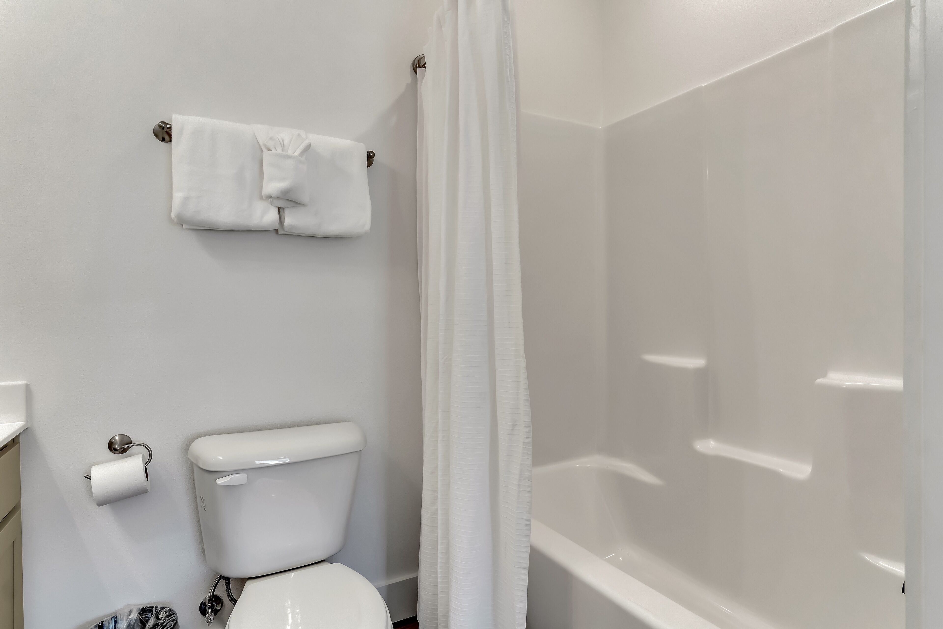 A bathroom with a toilet, a shower curtain, and a towel hanging on the wall.