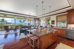 A spacious kitchen with a large island, wooden cabinets, and a view of the outdoors.