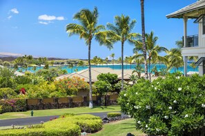 A resort with a pool, palm trees, and a view of the ocean.