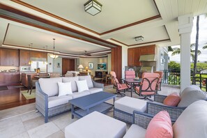 A spacious living area with a sofa, chairs, and a coffee table. A kitchen is visible in the background.