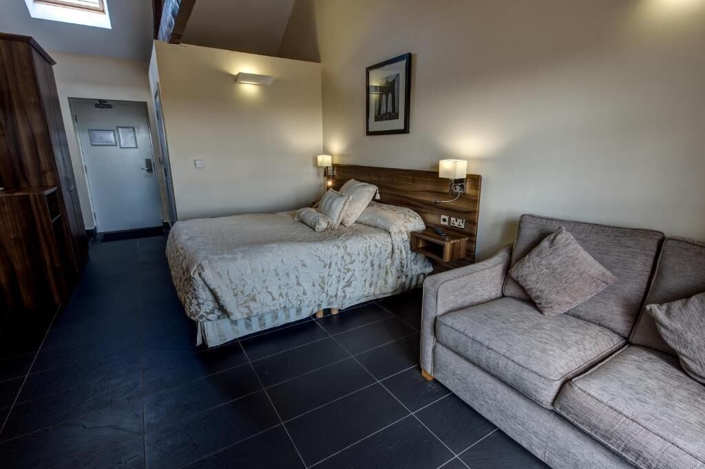 Een slaapkamer met een bed, een bank en een houten hoofdeinde.