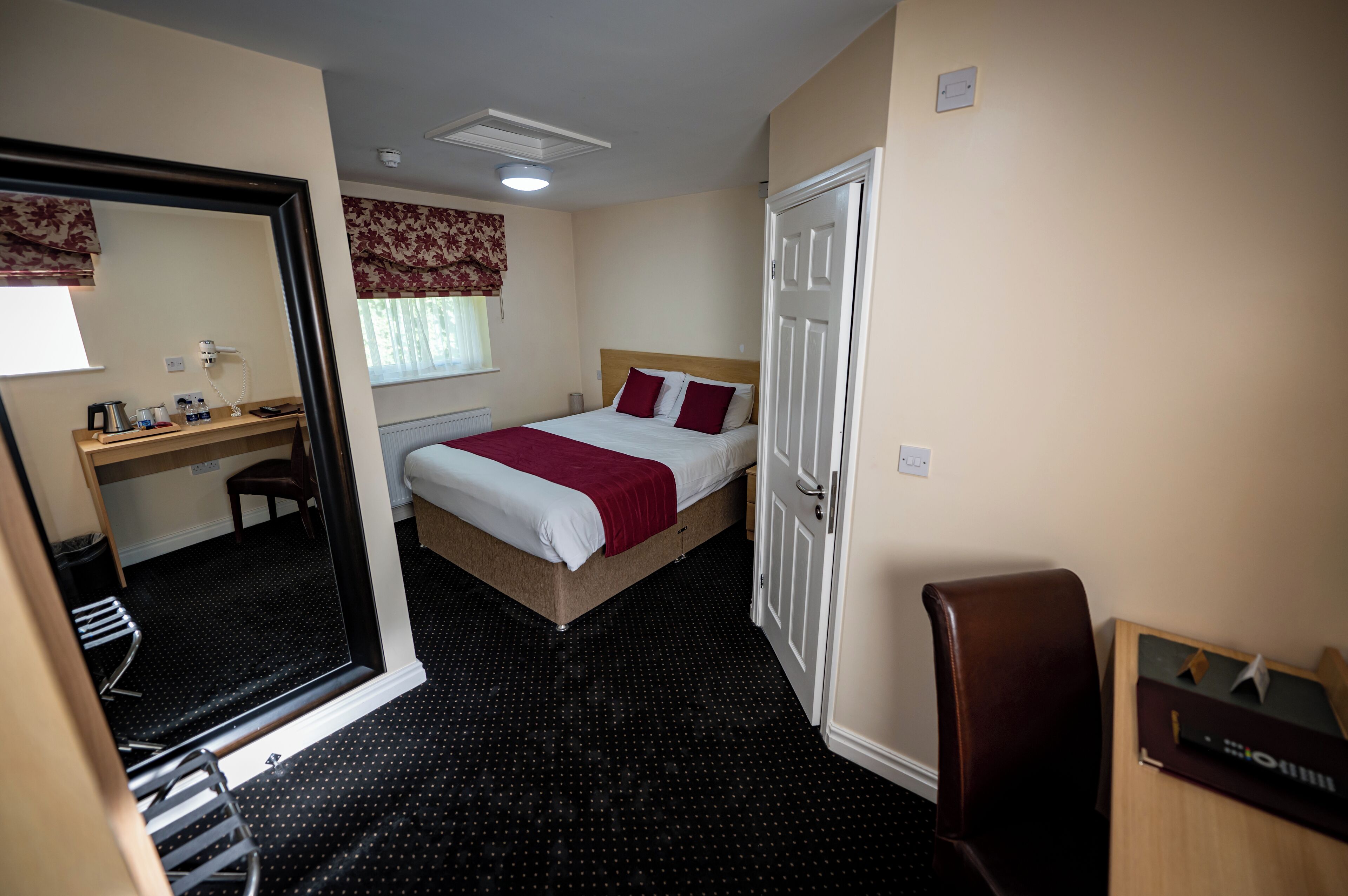 Une chambre d’hôtel comprenant un lit, un bureau, une chaise, une armoire et une salle de bain.