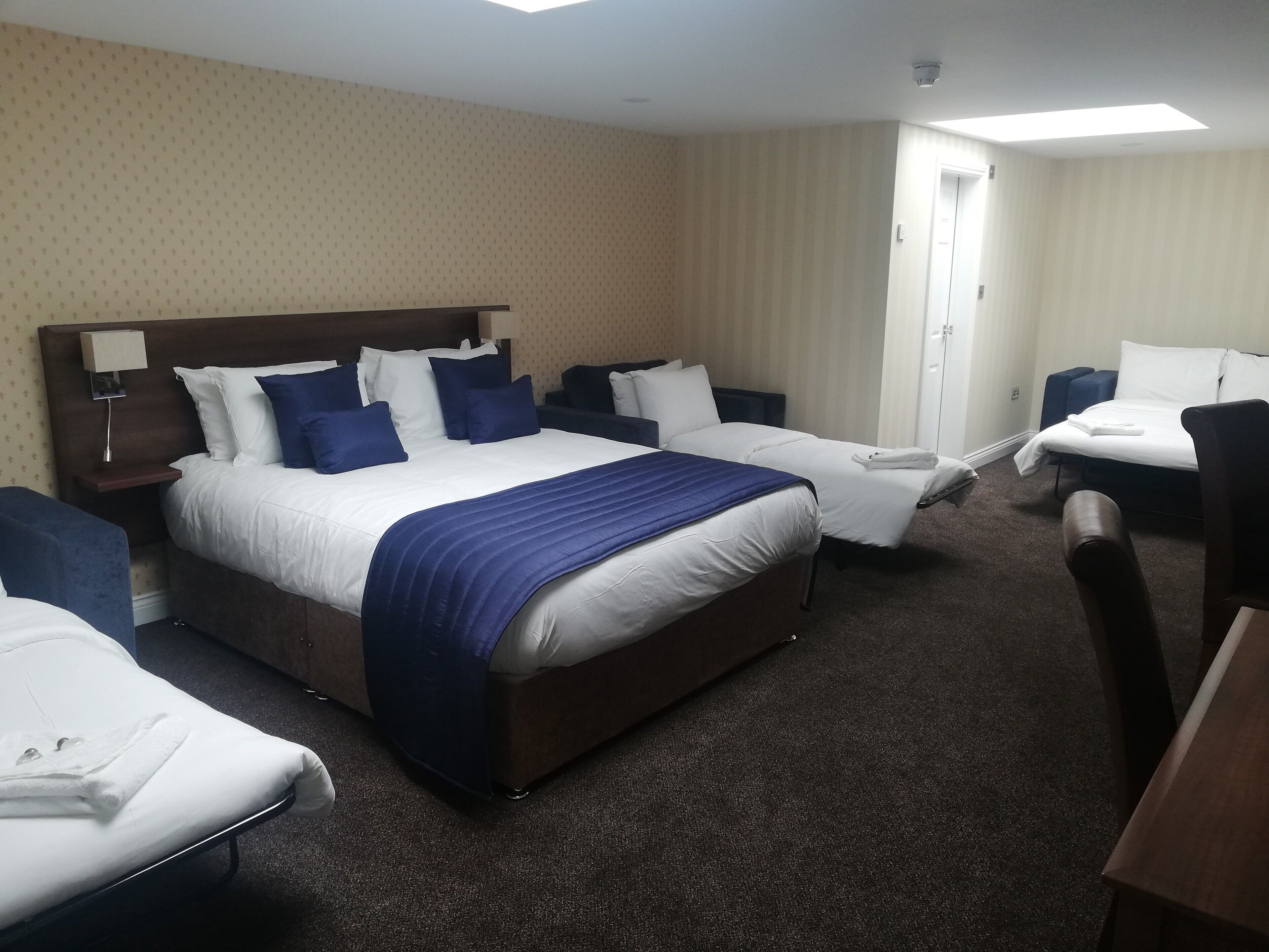 Une chambre d’hôtel avec un grand lit, deux tables de chevet, un bureau et une chaise.