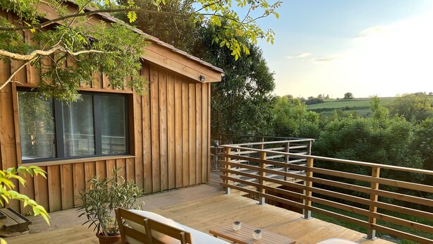 A wooden deck with a bench and table, overlooking a lush green landscape. - Le Petit Chai Fronsadais - Gite *** 5 persons (Saint-Michel-de-Fronsac)