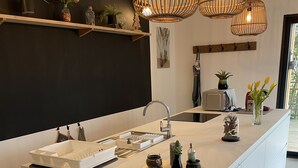 A modern kitchen with a central island, pendant lights, and a blackboard wall. - Le Petit Chai Fronsadais - Gite *** 5 persons (Saint-Michel-de-Fronsac)