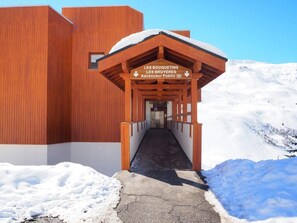 Ein Holzgebäude mit überdachtem Gang, der zu einem Eingang führt, auf dem 