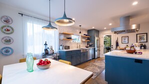 Uma cozinha moderna com armários azuis, uma ilha central e luminárias pendentes.