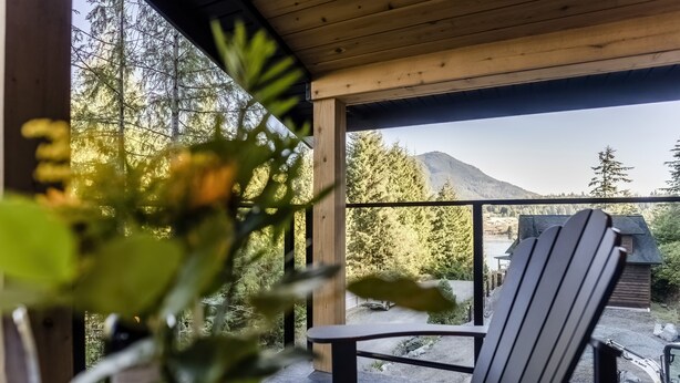 A wooden deck with a chair and table, overlooking a mountainous landscape with trees. - Sitka Cabin-Modern, Hikes, OD shower, Pet (Ucluelet)