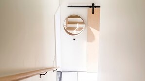 A narrow, well-lit hallway with a wooden handrail and a circular mirror on the wall. - Sitka Cabin-Modern, Hikes, OD shower, Pet (Ucluelet)